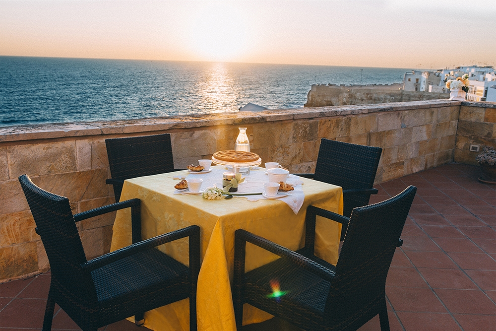 旅客可以在日落時分時前往義大利「莫諾波利」的「瑞萊斯德爾塞納托雷B&B」的露天陽台，看著金黃夕陽灑落在大海上，享受一頓美味晚餐。（圖片：Booking.com）